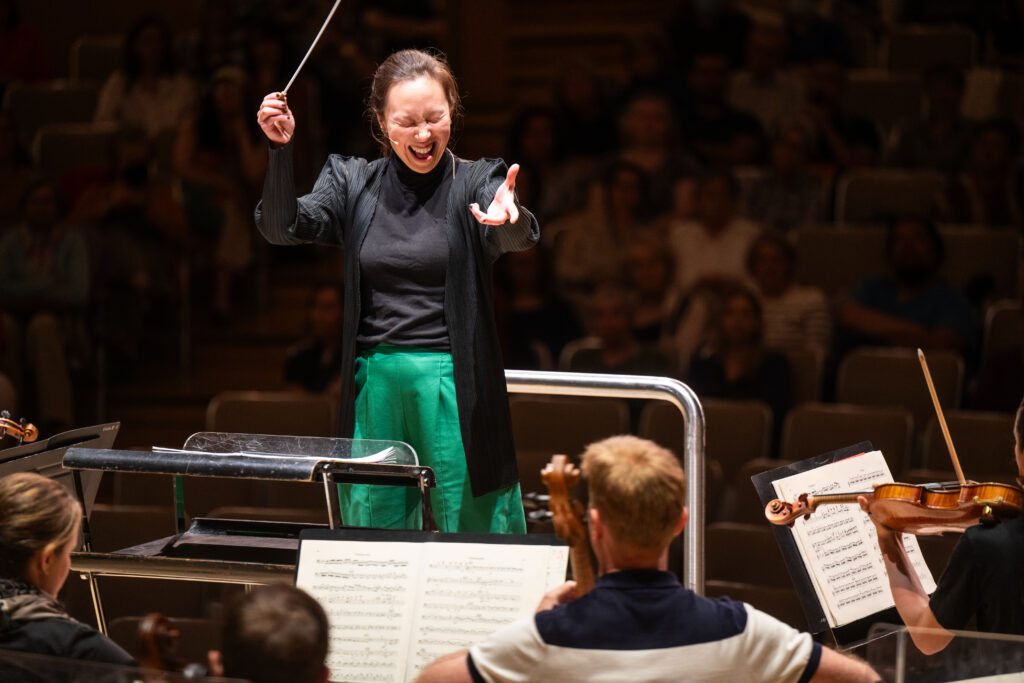 Conducting Fellow Naomi Woo stands on the conducting podium.