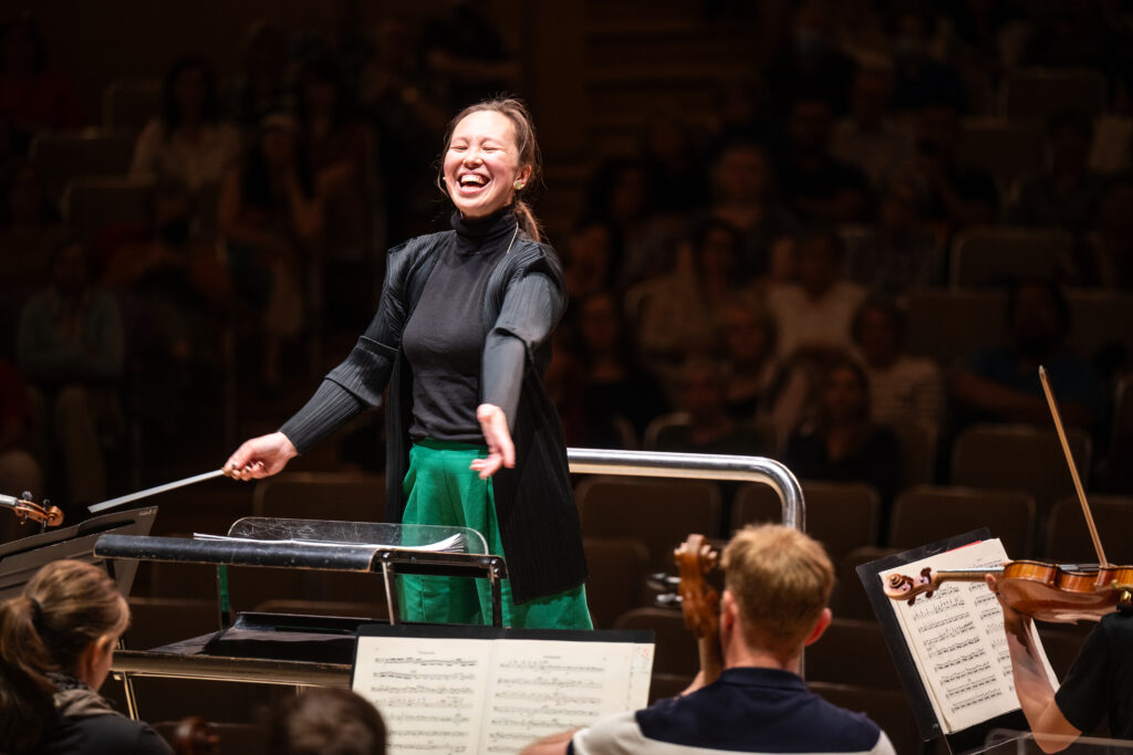 Conducting Fellow Naomi Woo stands on the conducting podium.