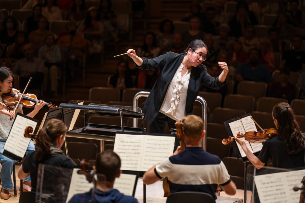 Conducting Fellow Jennifer Tung stands on the conducting podium.