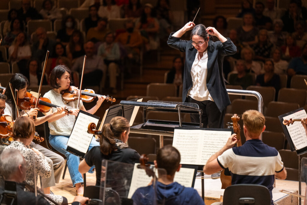 Conducting Fellow Jennifer Tung stands on the conducting podium.