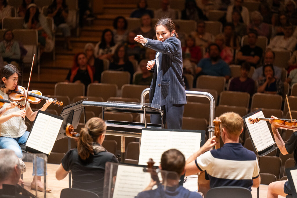 Conducting Fellow Kelly Lin stands on the conducting podium.