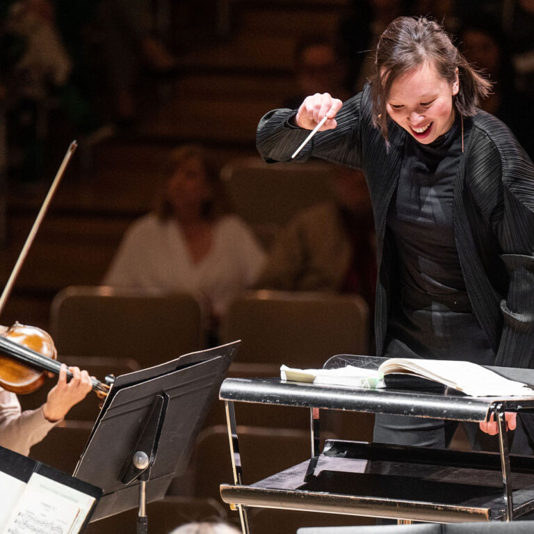 Naomi Woo conducting on a podium