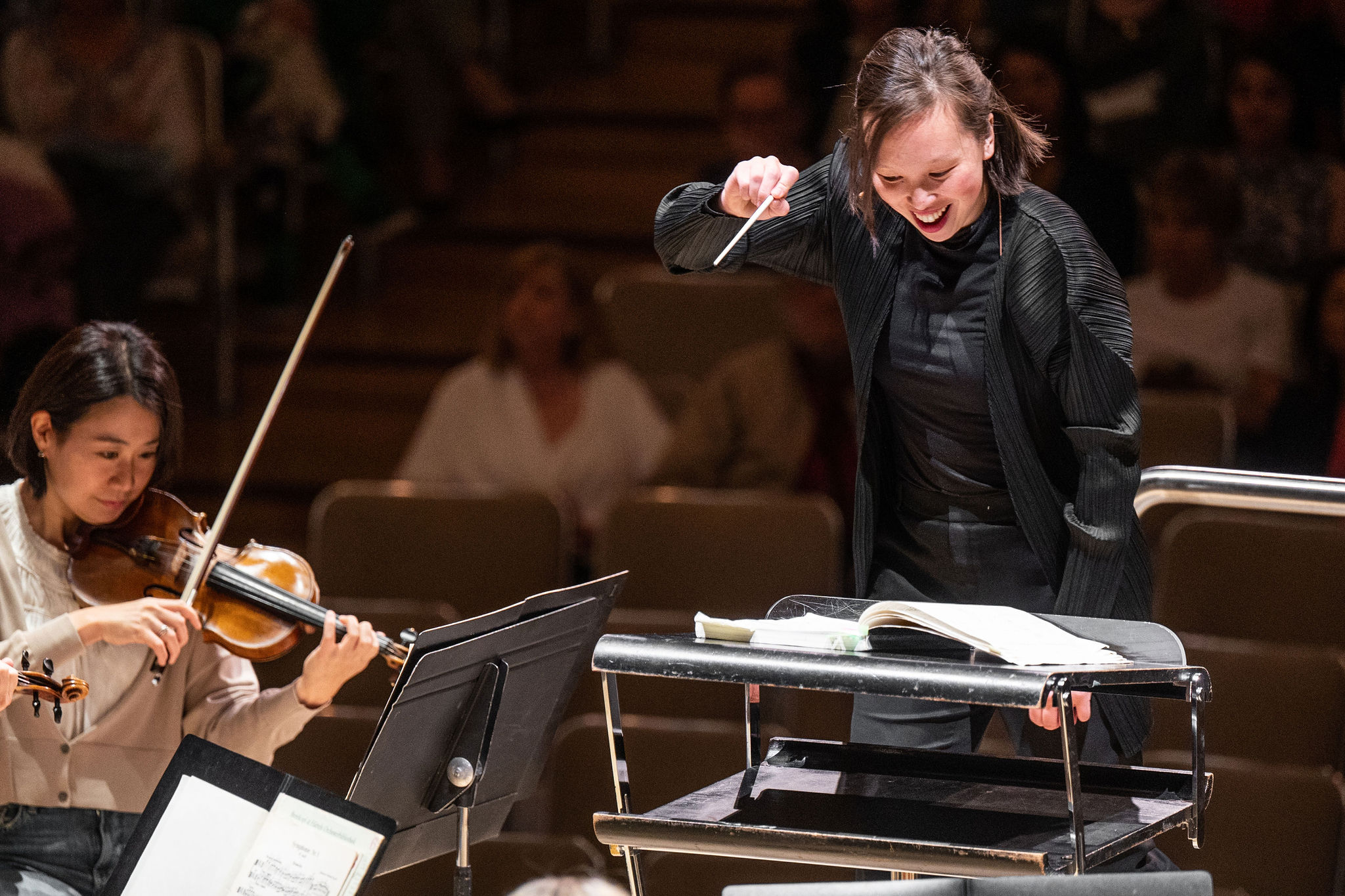 Naomi Woo conducting on a podium