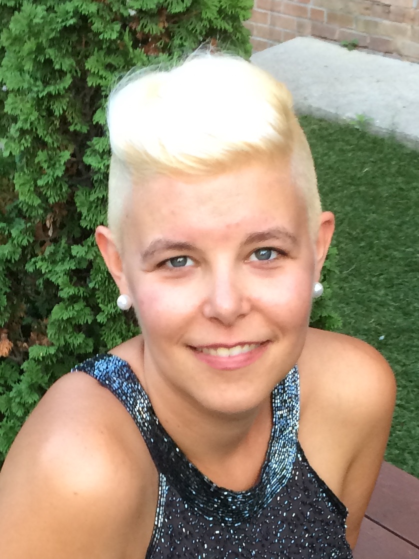A picture looking down at a blonde white woman, shown from the shoulders up, turned slightly towards the camera.